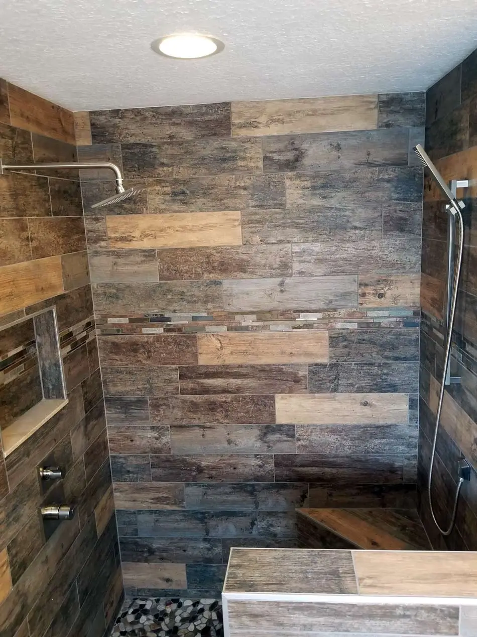 Custom tile shower with wood-look porcelain, glass mosaic accent and a pebble floor